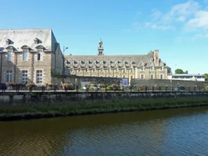 Ancien couvent des Augustins en granite sur la rive gauche du Léguer à Lannion, avec promenade fleurie au bord de l'eau, Côtes-d'Armor, Bretagne